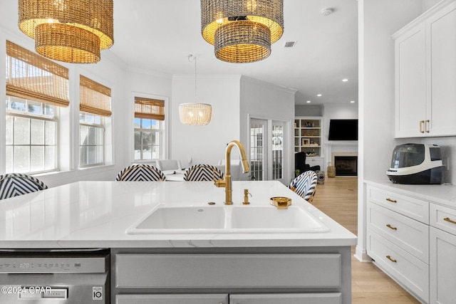 kitchen featuring dishwasher, an island with sink, sink, and white cabinetry