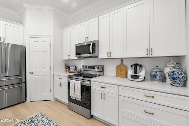 kitchen featuring ornamental molding, white cabinetry, appliances with stainless steel finishes, light stone countertops, and light hardwood / wood-style floors