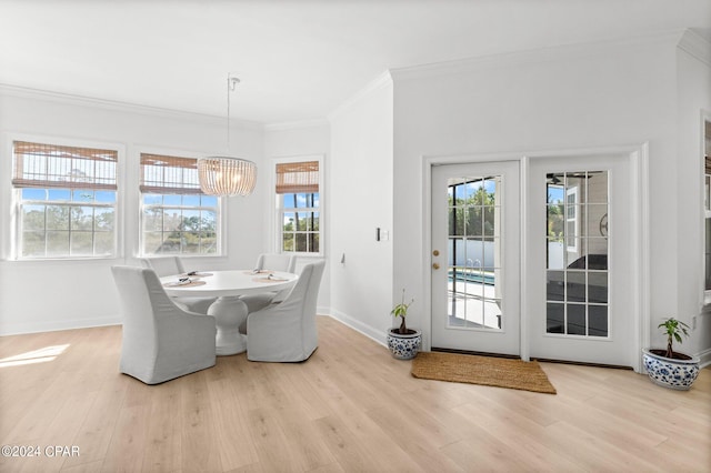 dining space with an inviting chandelier, light hardwood / wood-style flooring, and crown molding