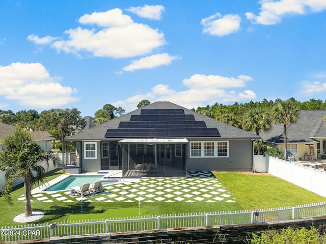 back of property featuring a patio, a fenced in pool, a sunroom, solar panels, and a lawn