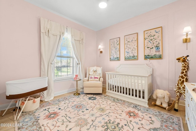 bedroom featuring a nursery area and wood-type flooring