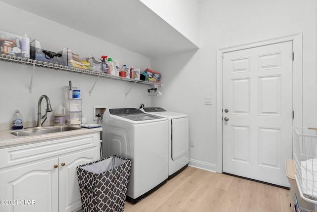 washroom with cabinets, washer and clothes dryer, sink, and light hardwood / wood-style flooring