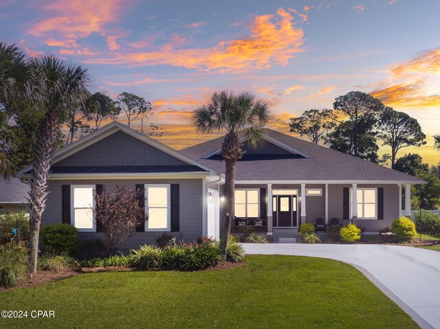 single story home with a lawn and covered porch