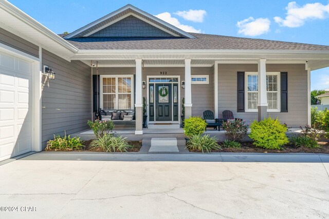 view of exterior entry featuring a porch and a garage