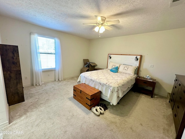 carpeted bedroom with ceiling fan and a textured ceiling