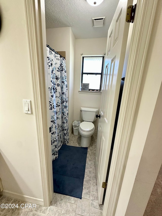 bathroom with toilet and a textured ceiling