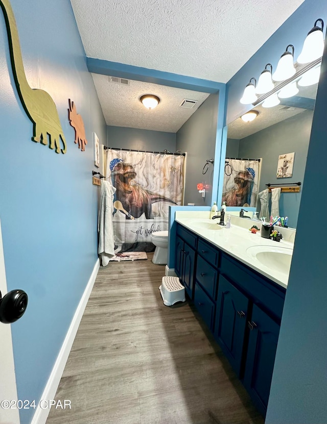 bathroom featuring toilet, wood-type flooring, a shower with curtain, vanity, and a textured ceiling