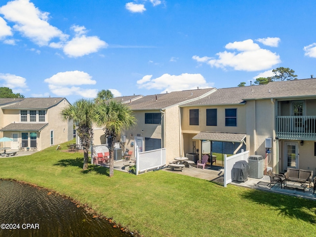 rear view of property featuring a yard, central AC, and a patio area