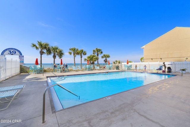 view of pool with a water view and a patio