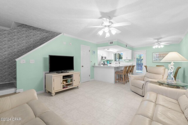 living room featuring ceiling fan, crown molding, and a textured ceiling