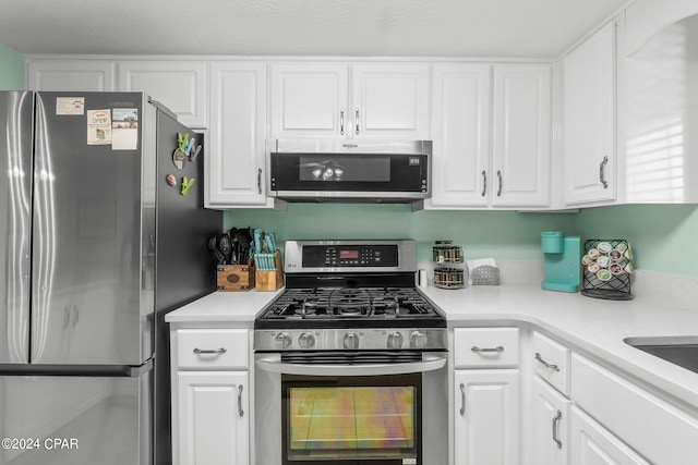 kitchen with white cabinets, stainless steel appliances, and a textured ceiling