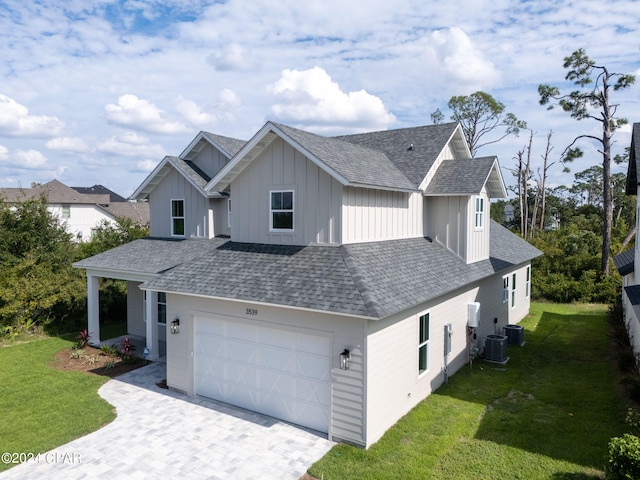 view of front of house with cooling unit, a garage, and a front lawn