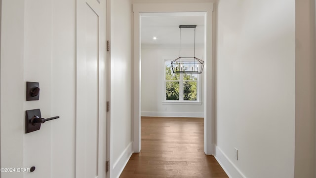 corridor featuring a notable chandelier and dark wood-type flooring