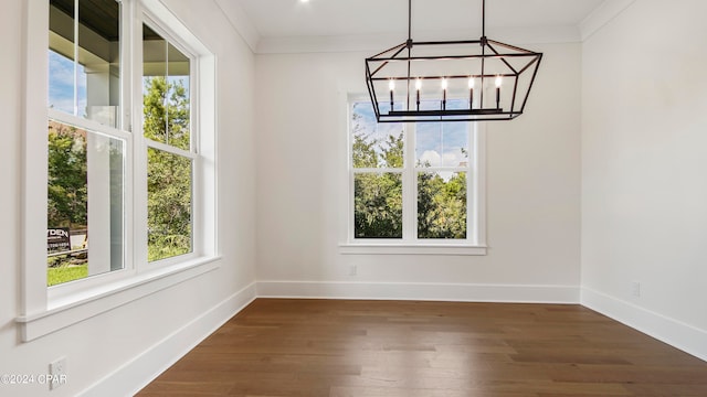 unfurnished dining area with an inviting chandelier, dark hardwood / wood-style floors, and ornamental molding