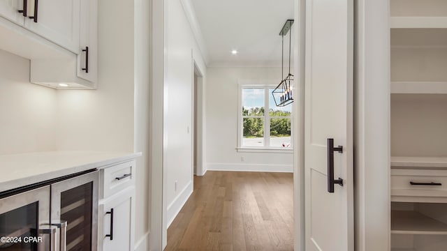 hall with crown molding, beverage cooler, and wood-type flooring