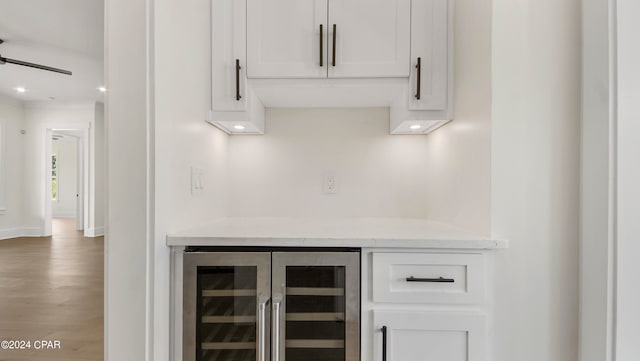 bar featuring light stone countertops, hardwood / wood-style floors, wine cooler, and white cabinetry