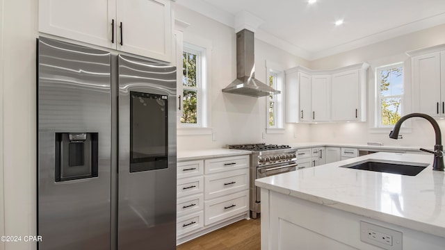 kitchen featuring stainless steel appliances, wall chimney range hood, and white cabinetry