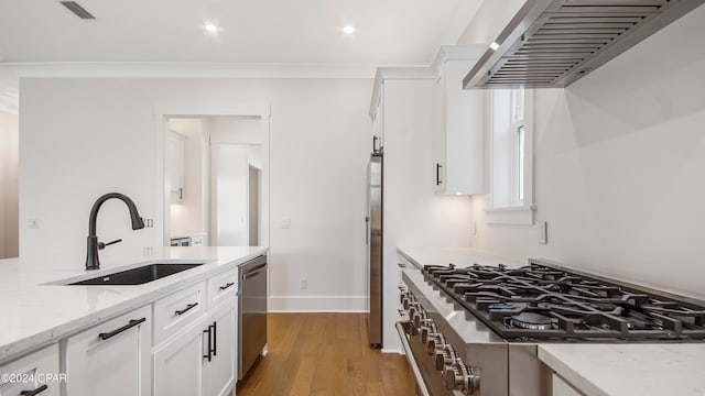 kitchen featuring light stone counters, stainless steel appliances, ventilation hood, sink, and white cabinetry