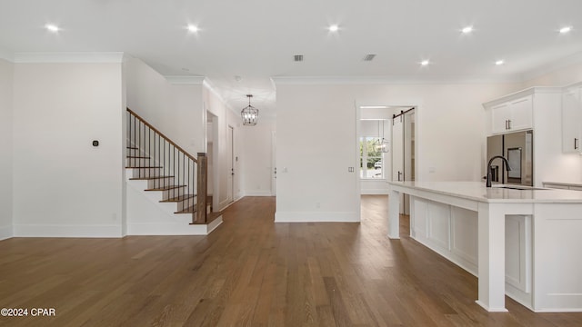 kitchen featuring crown molding, dark hardwood / wood-style floors, stainless steel refrigerator with ice dispenser, a spacious island, and white cabinetry