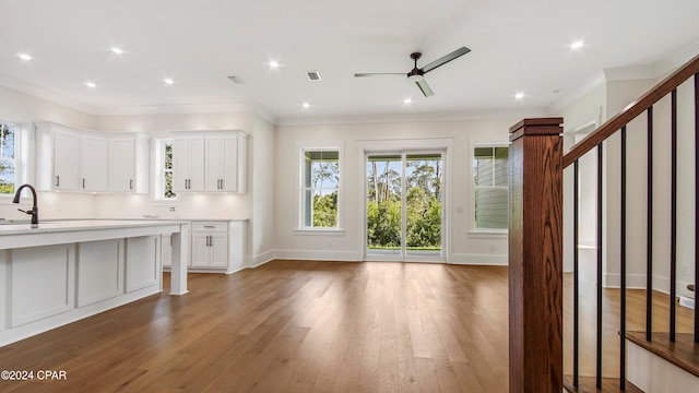 kitchen with ceiling fan, hardwood / wood-style flooring, ornamental molding, and white cabinetry