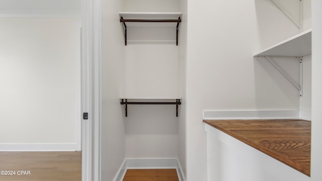 walk in closet with light hardwood / wood-style flooring