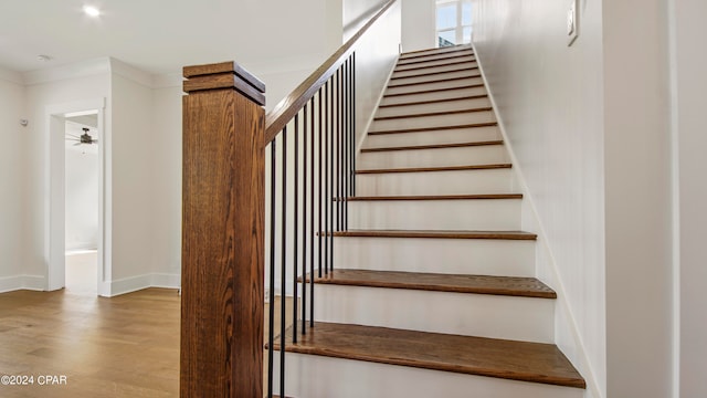 stairway with ornamental molding and hardwood / wood-style flooring