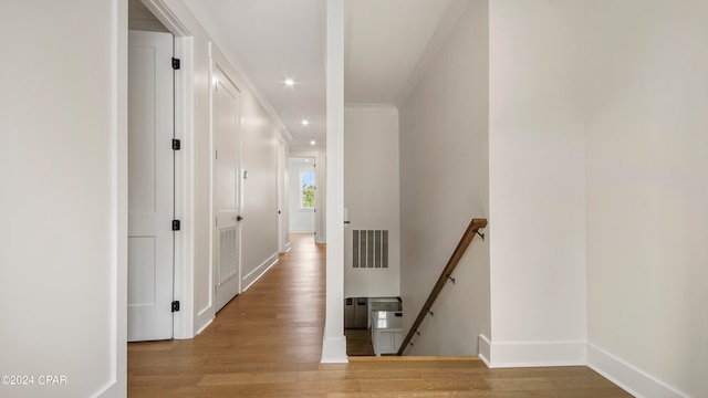 hallway featuring ornamental molding and light hardwood / wood-style floors