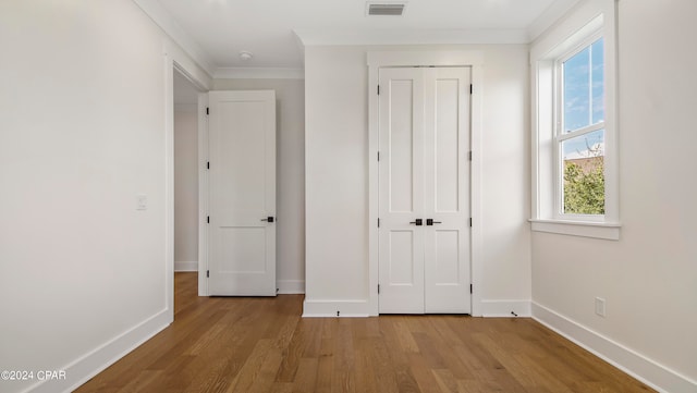 unfurnished bedroom featuring ornamental molding and light hardwood / wood-style floors