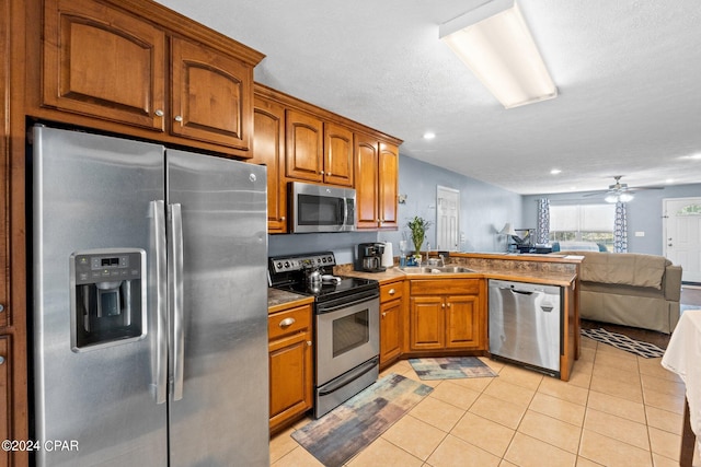 kitchen featuring a textured ceiling, sink, light tile patterned floors, ceiling fan, and appliances with stainless steel finishes