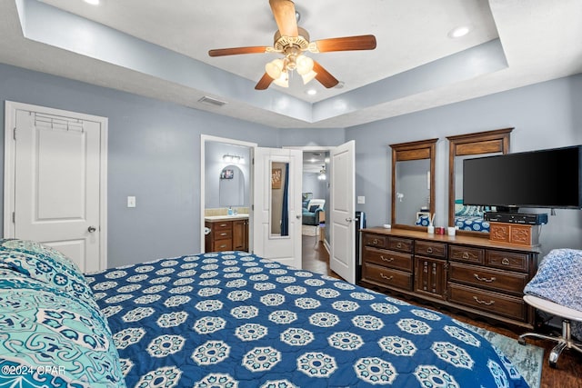 bedroom with ceiling fan, connected bathroom, and a raised ceiling