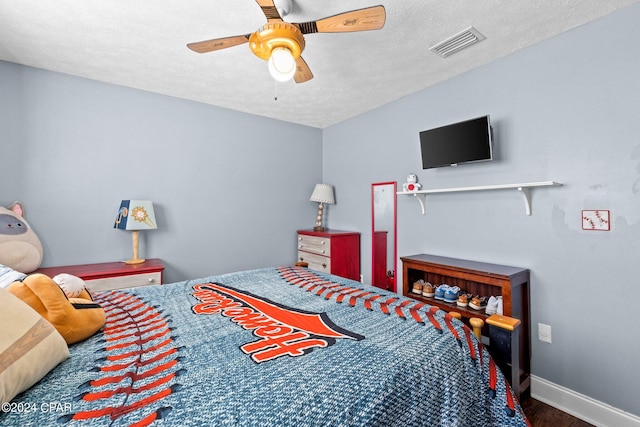 bedroom with a textured ceiling, wood-type flooring, and ceiling fan