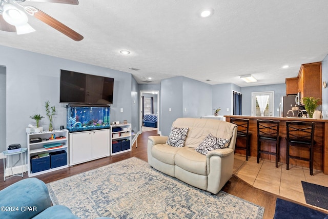 living room with a textured ceiling, hardwood / wood-style flooring, and ceiling fan