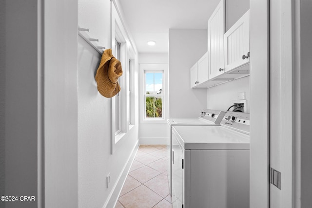 laundry area with light tile patterned flooring, washing machine and clothes dryer, and cabinets