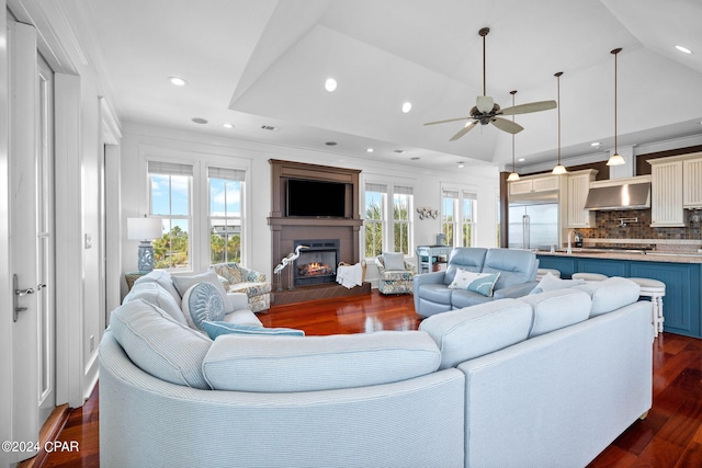 living room featuring ceiling fan, sink, ornamental molding, dark wood-type flooring, and vaulted ceiling