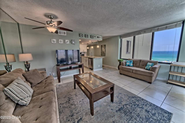 living area with light tile patterned floors, ceiling fan, a textured ceiling, and visible vents