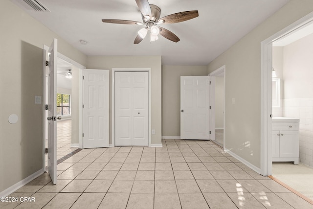 unfurnished bedroom with ceiling fan, ensuite bathroom, a closet, and light tile patterned floors