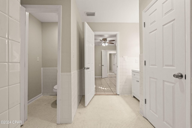 bathroom with ceiling fan, tile walls, tile patterned flooring, and toilet