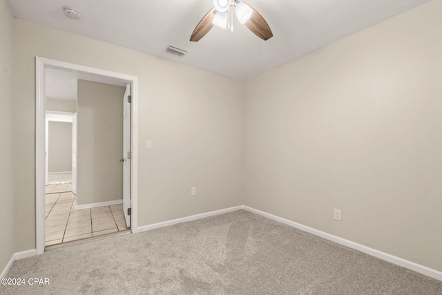 empty room with ceiling fan and light carpet