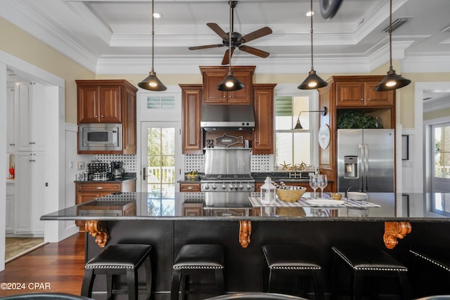 kitchen with dark hardwood / wood-style flooring, stainless steel appliances, a breakfast bar area, and dark stone countertops