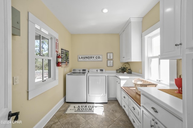 laundry room with cabinets, dark tile patterned floors, and washing machine and clothes dryer