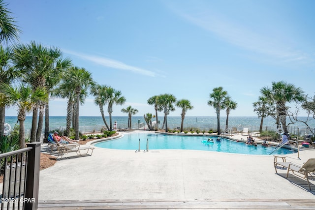 view of pool featuring a water view and a patio