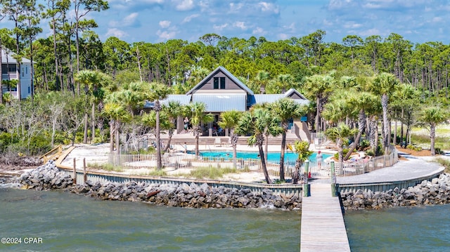 dock area with a water view, a patio, and a community pool