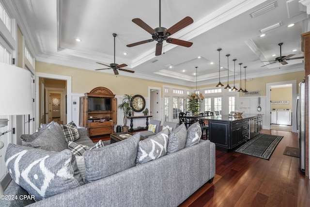 living room featuring ornamental molding, independent washer and dryer, a raised ceiling, and dark wood-type flooring