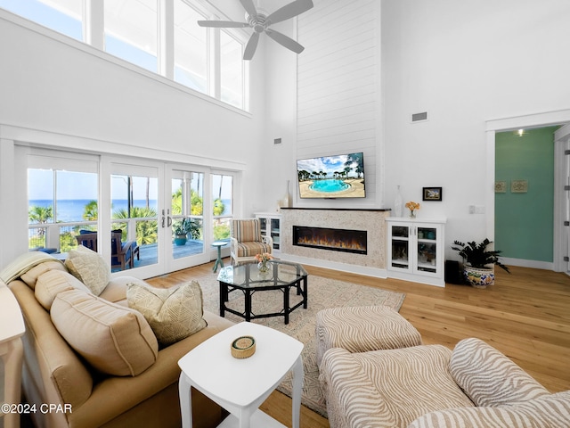 living room with a high ceiling, french doors, light hardwood / wood-style floors, and ceiling fan