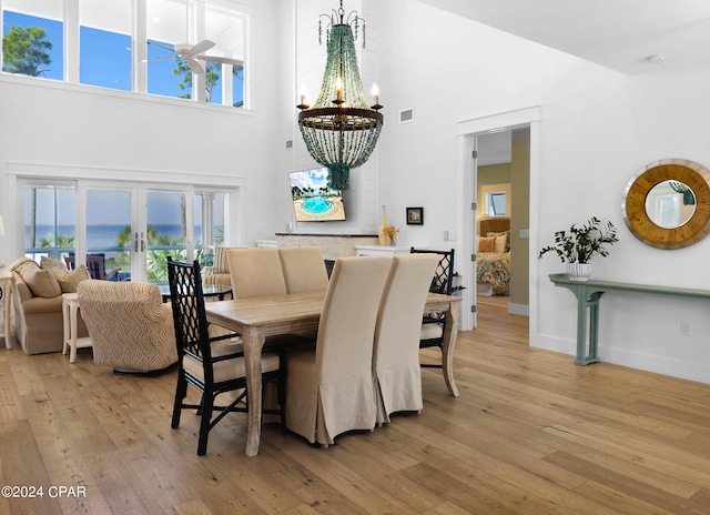 dining room with a notable chandelier, light wood-type flooring, a towering ceiling, and french doors