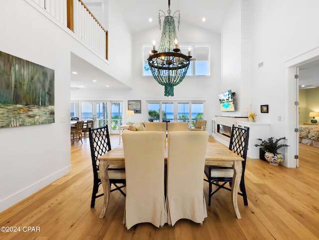 dining area featuring light hardwood / wood-style flooring, high vaulted ceiling, and a notable chandelier