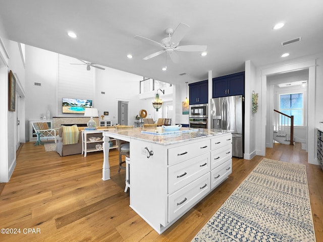 kitchen featuring a breakfast bar, light hardwood / wood-style floors, blue cabinetry, and appliances with stainless steel finishes