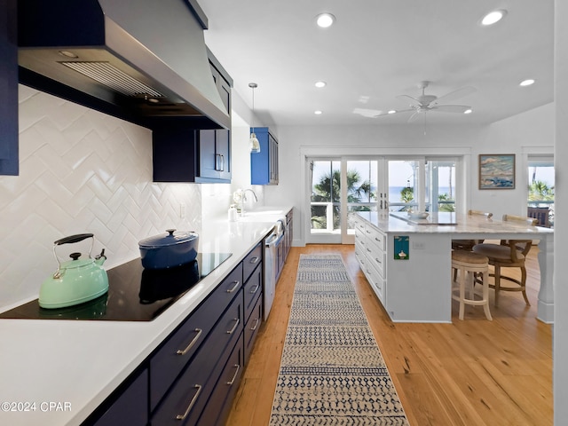 kitchen featuring french doors, wall chimney range hood, pendant lighting, a breakfast bar area, and light wood-type flooring