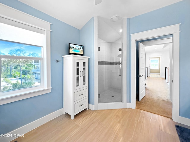 bathroom with hardwood / wood-style floors, walk in shower, and lofted ceiling