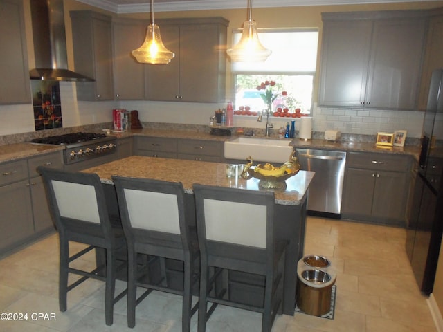 kitchen featuring wall chimney exhaust hood, crown molding, a breakfast bar area, sink, and stainless steel appliances